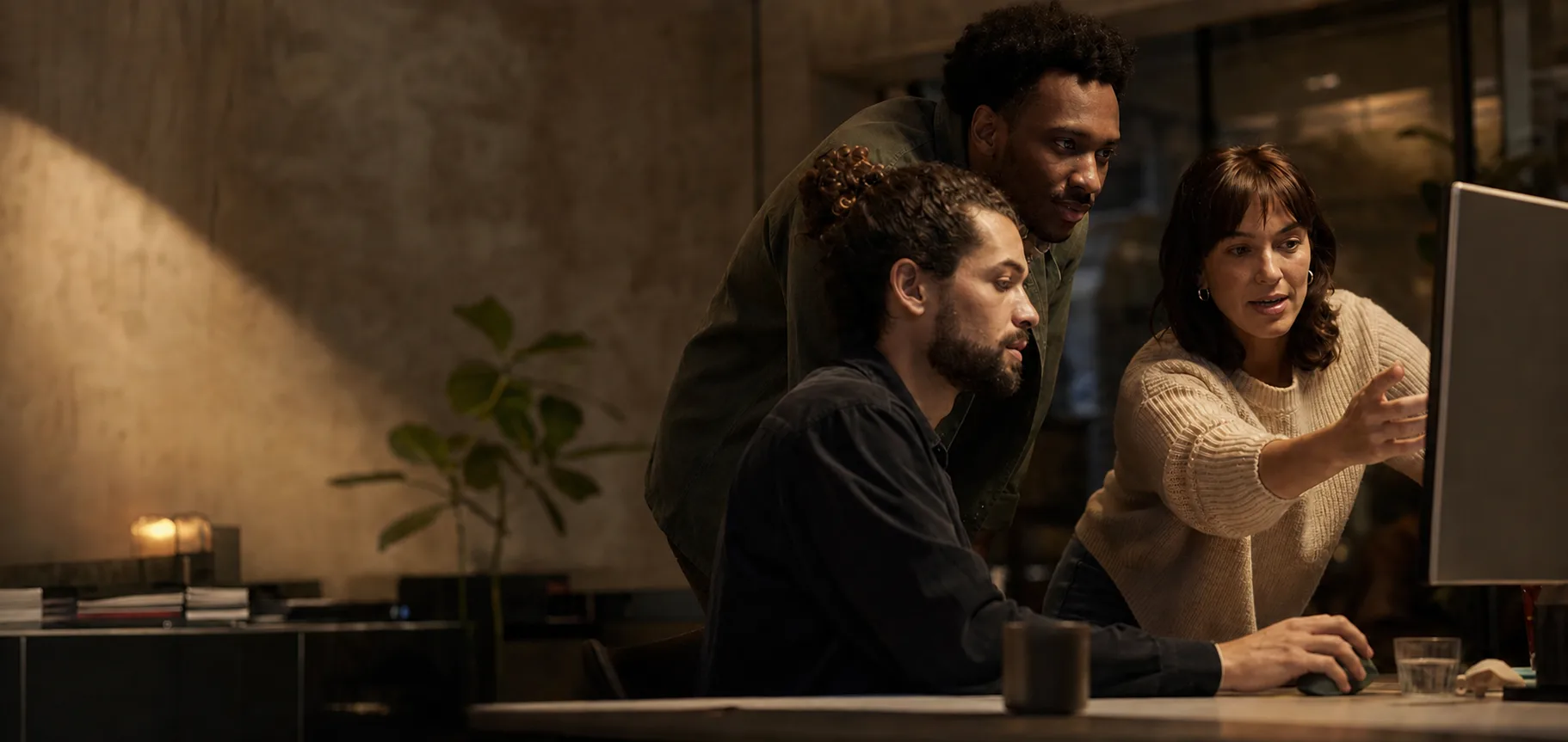 Coworkers collaborating around a desk in warm editorial lighting